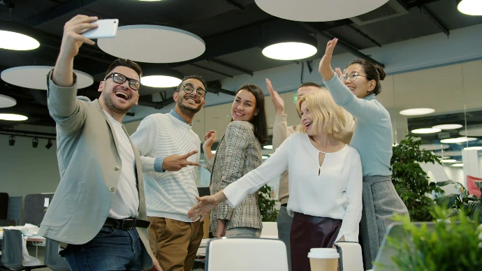 Diverse group of colleagues taking a selfie in office.
